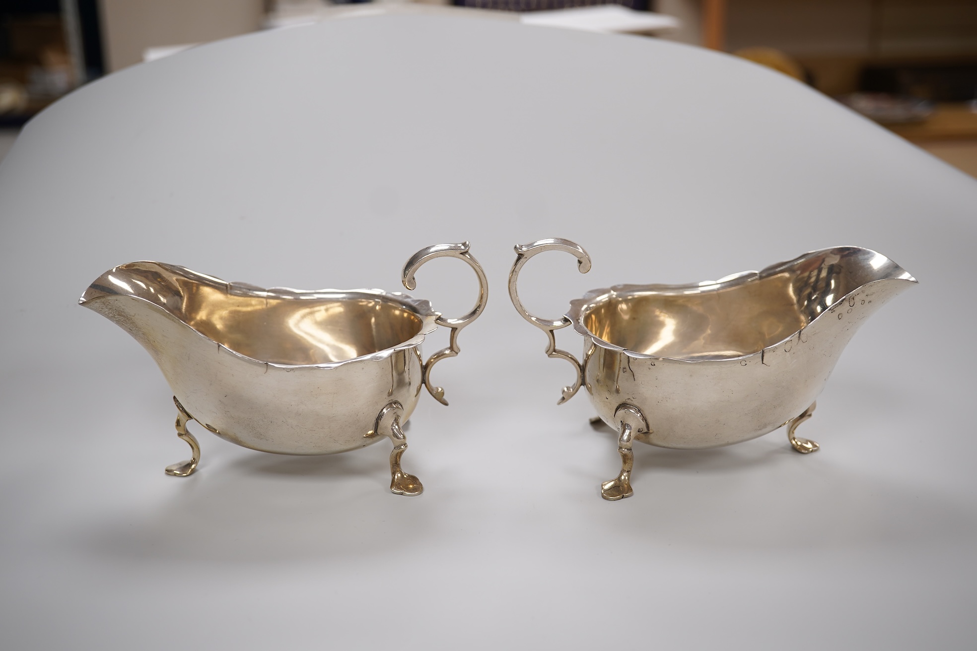 A pair of George V silver sauce boats, with flying scroll handles and pair of matching sauce ladles, Martin, Hall & Co, Sheffield, 1922/3, 10.1oz.